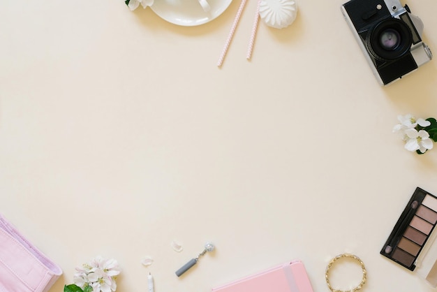 Female flat lay Spring flowers and women's cosmetics camera on a beige background Top view and copy space