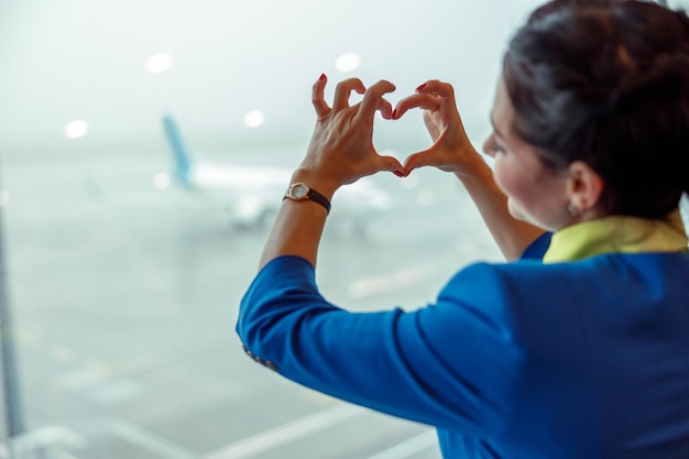 Female flight attendant doing heart symbol at airport