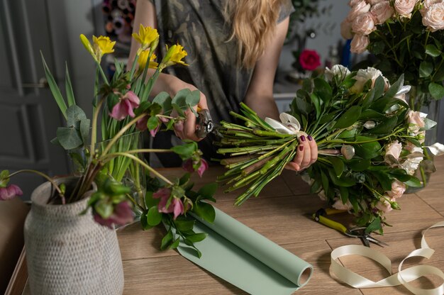 Female florist creating beautiful bouquet in flower shop, close up