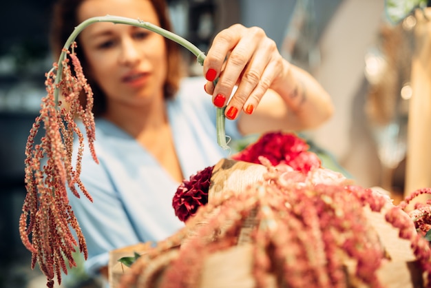 Female florist decorates with bunch flower bouquet in shop closeup. F