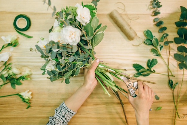 Photo female florist hands cuts flower composition with pruner