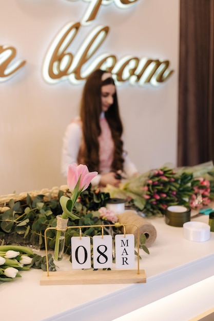 女性の花屋は、パック紙の美しい花の組成で春の花の美しい花束を保持します