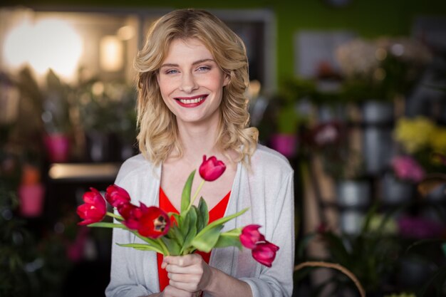 Female florist holding bunch of flower in flower shop