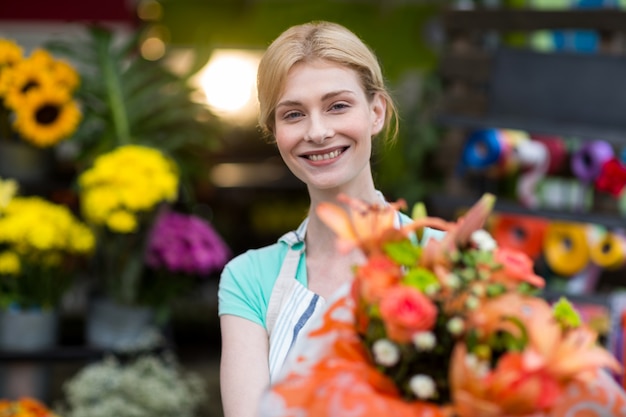 Female florist holding flower bouquet in flower shop