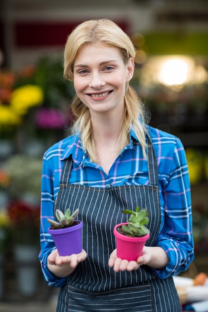 Female florist holding plant pot in flower shop