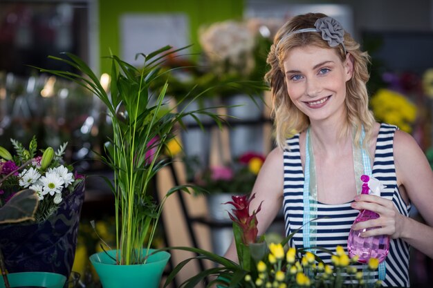 スプレーボトルを保持している女性の花屋