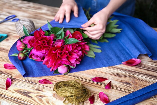 Photo female florist making bouquet of beautiful peonies in flower shop closeup