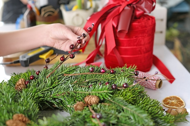 Female florist making Christmas wreath  in flower shop