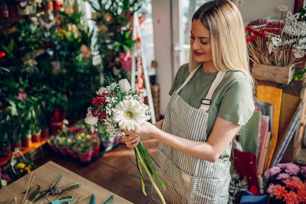 Fiorista femminile che fa un mazzo di fiori freschi in un negozio di fiori