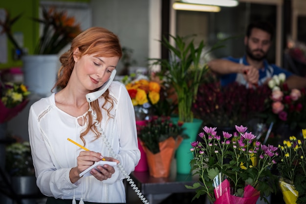 電話で注文を取る女性の花屋