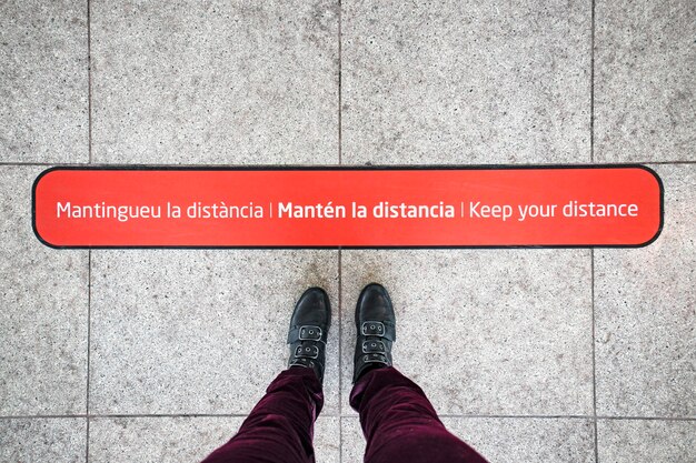 スペインの国際空港の乗客のための床の女性の足と社会的距離のサイン