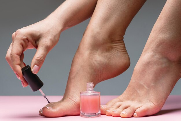 Female foot with beautiful french pedicure woman applying pink
nail polish on toenails