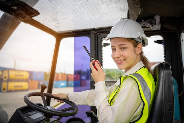 女性職長フォーク リフト コンテナー貨物フォーク リフトを運転し、運転制御フォーク リフト コンセプト サービスと輸送物流中の通信にトランシーバーを使用します。