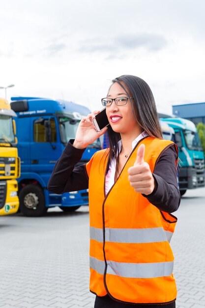 Female forwarder in front of trucks on a depot