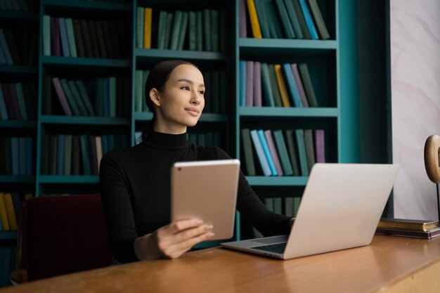 여성 프리랜스 디자이너는 노트북 컴퓨터를 사용하여 인터넷 서핑을 하는 현대적인 사무실에서 일하고 있습니다.