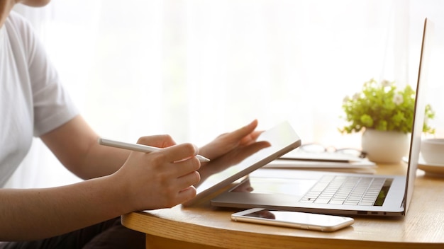 Female freelancer or college student using digital tablet touchpad in her minimalist workspace