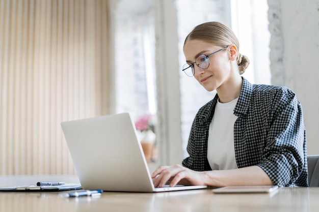 オフィスで働く女性のフリーランサー マネージャーは、会社でコンピューター レポートを使用します。