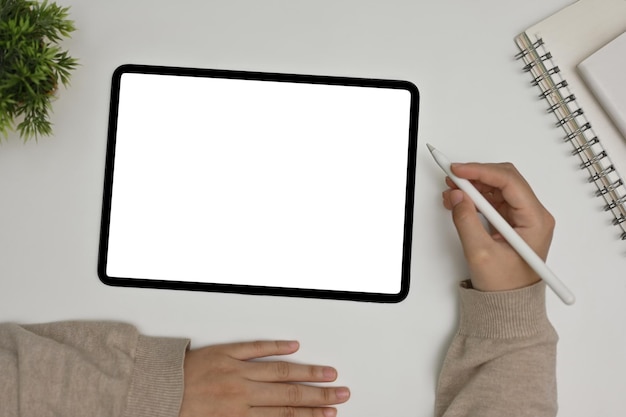 Una donna freelance che utilizza la tavoletta digitale area di lavoro con tablet mockup sulla vista dall'alto del tavolo bianco