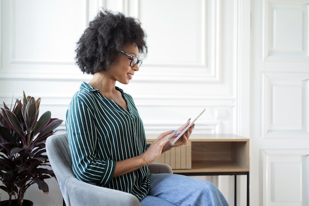 A female freelancer with glasses uses a tablet to make a report online Manager in business glasses