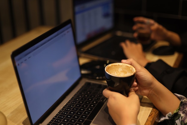 Female freelancer working online at computer while holding coffee mug. Concept of networking and occ