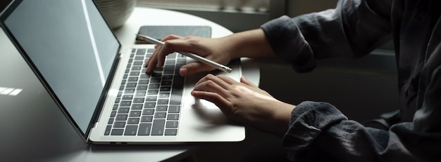 Female freelancer working with laptop on circle table next to the window in living room