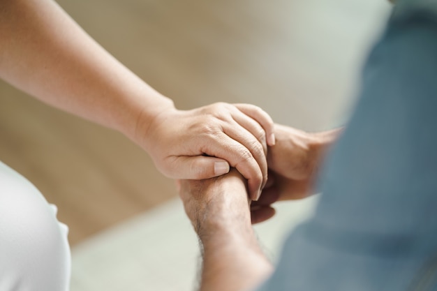 Female friend or family sitting and hold hands during cheer up to mental depress man, Psychologist provides mental aid to patient. PTSD Mental health concept