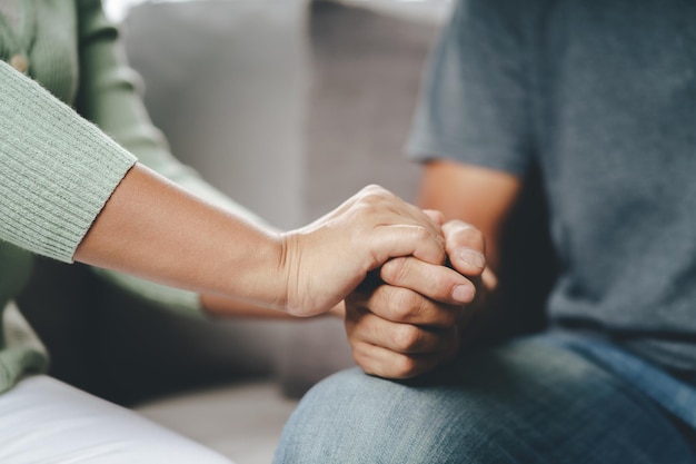 Female friend or family sitting and hold hands during cheer up to mental depress man