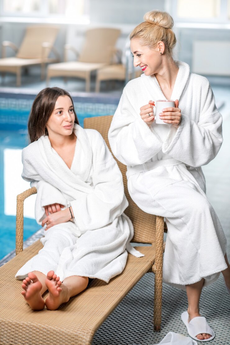 Photo female friends in bathrobes relaxing together near the basin in the spa