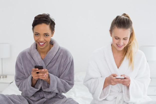 Женские друзья в халатах текстовые сообщения на кровати