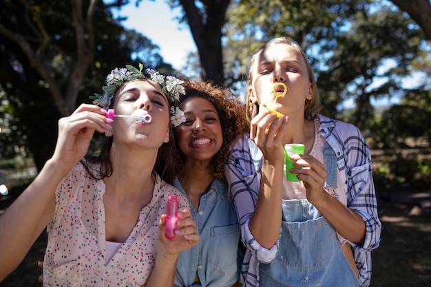 Female friends blowing bubbles in park