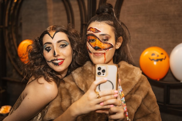 Female friends in costumes at the halloween party with friends in a disco nightclub