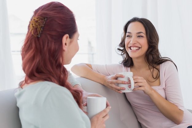 Female friends enjoying a chat with coffee cups at home