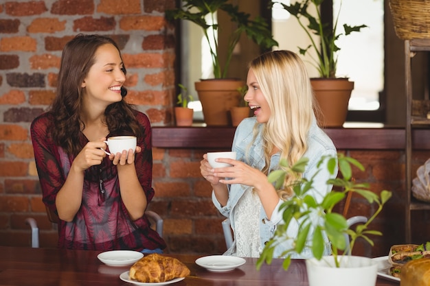 コーヒーショップでコーヒーを持っている女性の友達