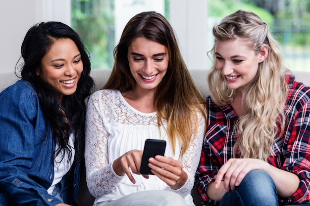 Female friends looking in mobile phone while sitting at home