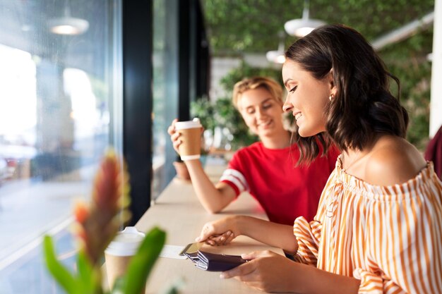 female friends paying by credit card at cafe