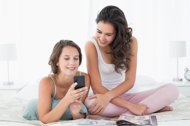 Foto amici femminili che leggono messaggio di testo a letto