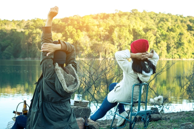 Photo female friends sitting on chair at riverbank