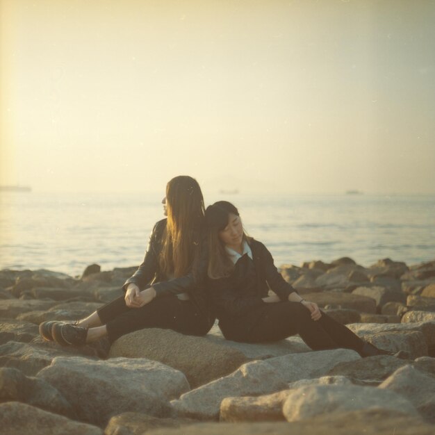 Photo female friends sitting on rock against sky