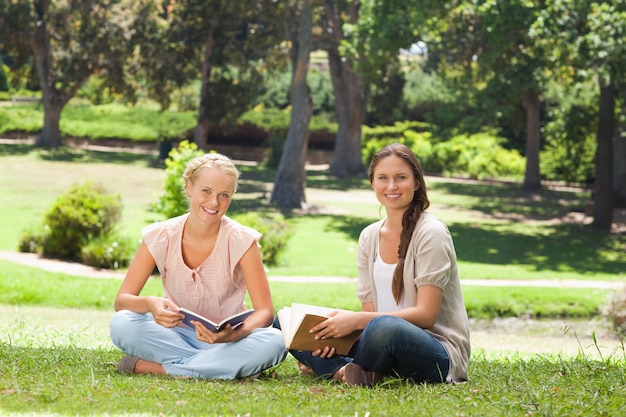 Женщины-друзья сидят со своими книгами в парке