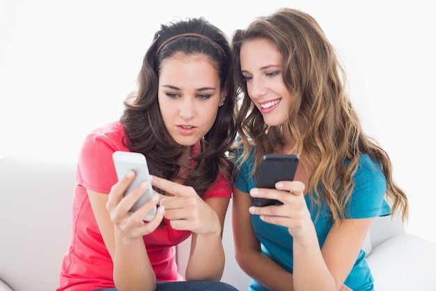 Female friends in sunglasses reading text message