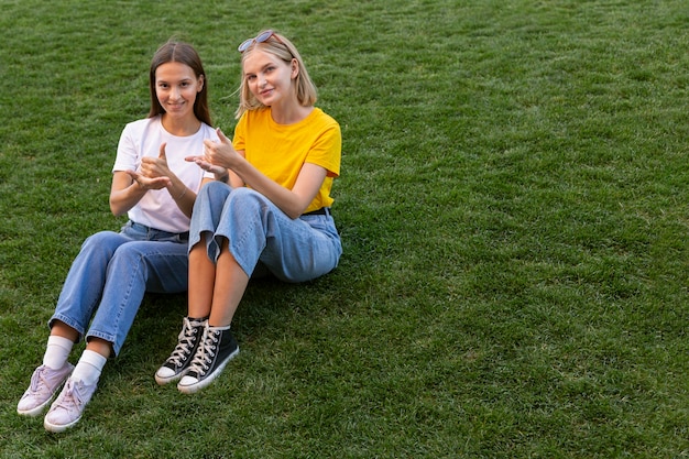 Female friends using sign language outside with copy space