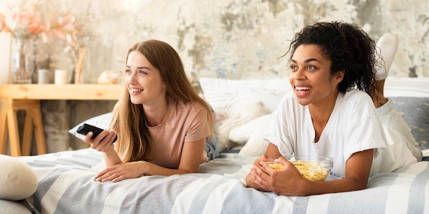 Foto amici femminili che guardano la tv a casa con popcorn