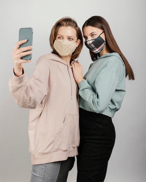 Photo female friends wearing masks and taking selfie