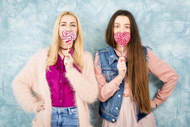 Female friends with candy on the blue background