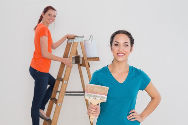 Female friends with paint brushes and ladder