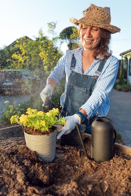 A female gardener sprays a plant with a water sprayer in the garden