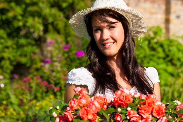 Female gardener with straw hat posing with flowers