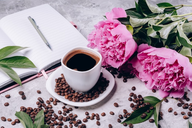 Female gift of coffee and peonies with notepad