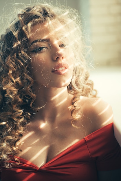 Female glamour face with long blonde hairstyle. Beautiful woman with curly hair and perfect makeup