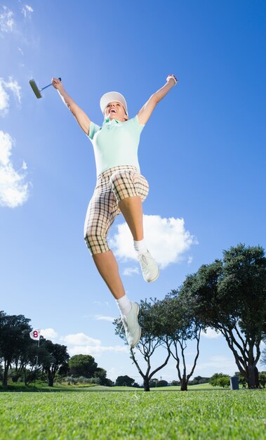 Female golfer leaping and cheering